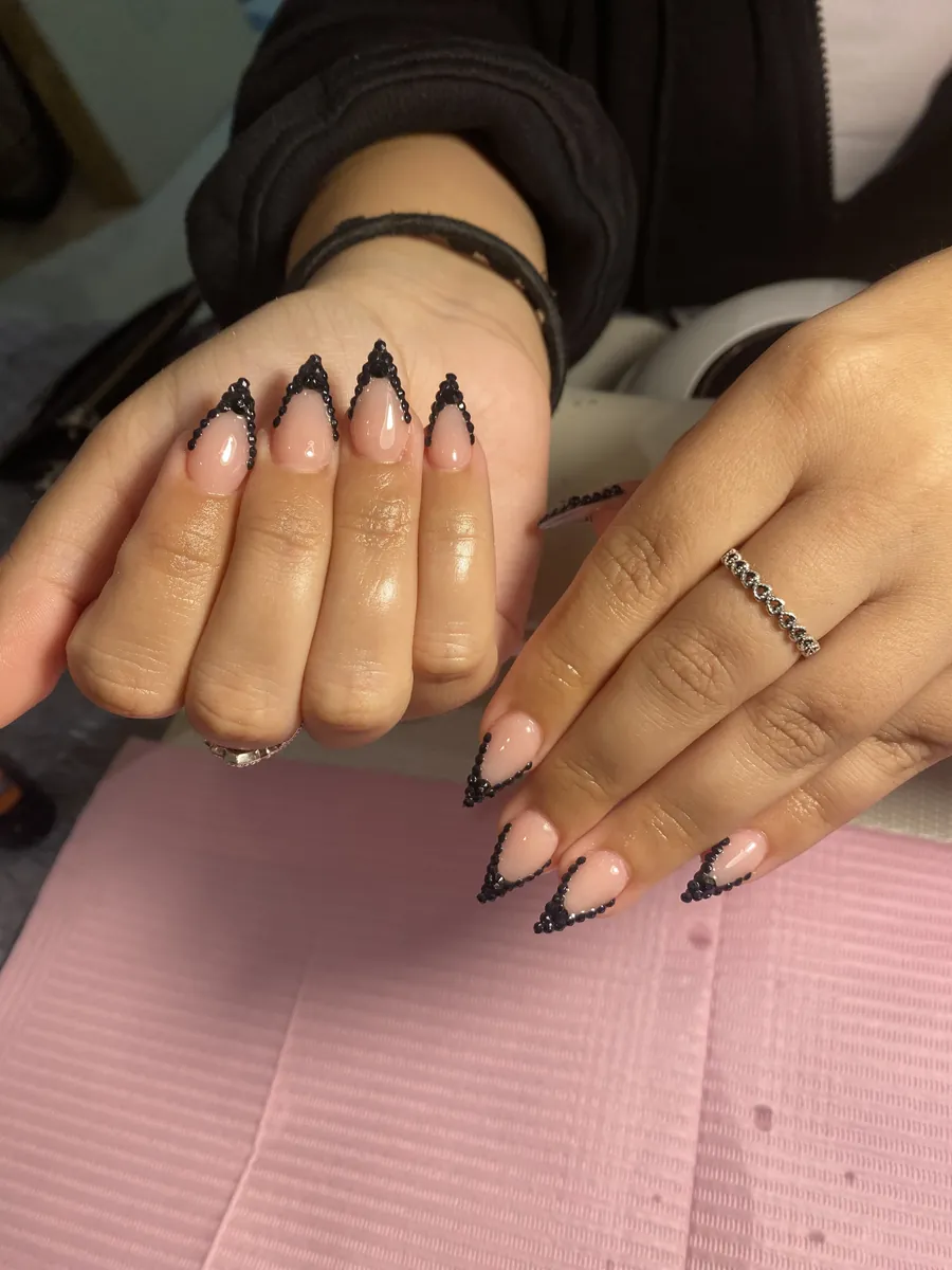 Nude almond nails with black rhinestone V-tips